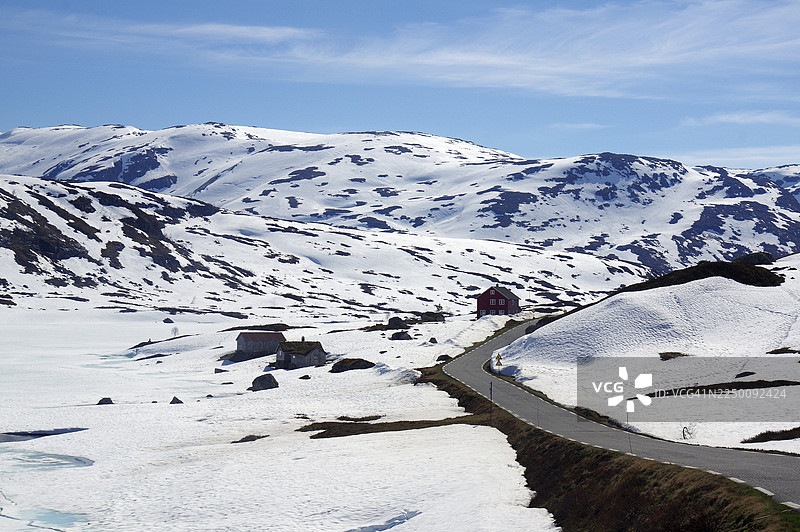 雪山景观，有道路和散落的房屋，在蓝天下，五月，春天，高拉菲耶尔山，挪威图片素材