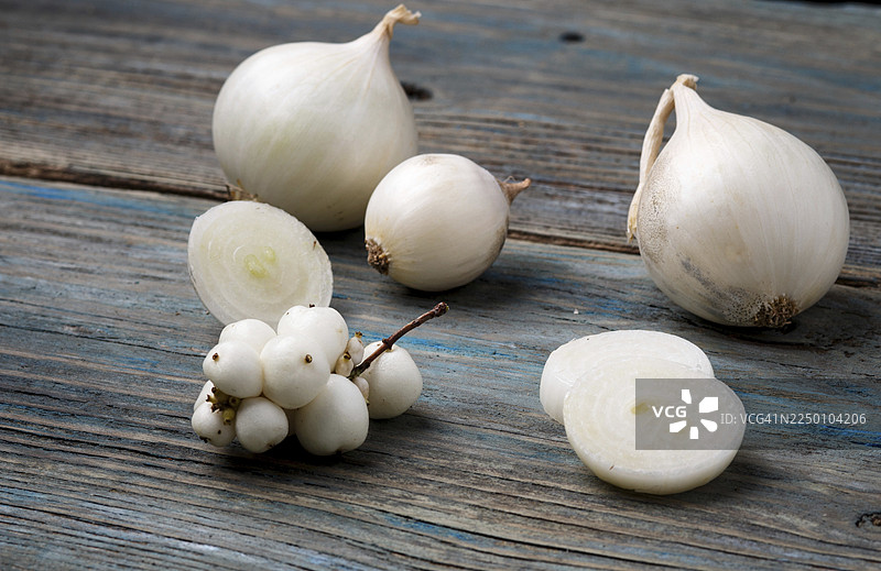 蓝色的乡村木质背景上的白洋葱和白色浆果图片素材