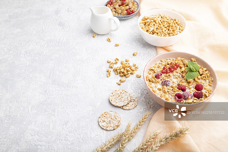 陶瓷碗里的麦片粥，配有牛奶、覆盆子和醋栗，放在灰色混凝土背景和橙色亚麻布上。俯视角度，留有复制空间。图片素材