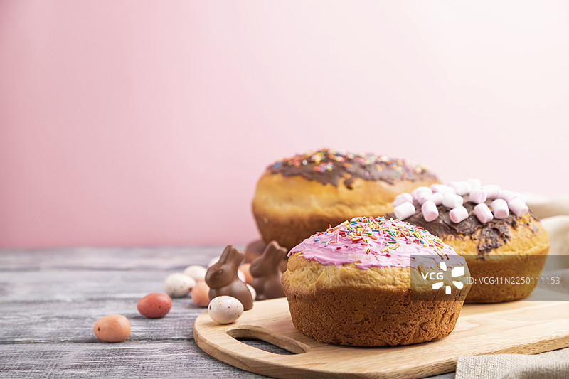 自制的釉面和装饰的复活节派，配有巧克力彩蛋和兔子，背景为灰色和粉色，搭配亚麻纺织品。侧视图，选择性对焦，可复制空间图片素材