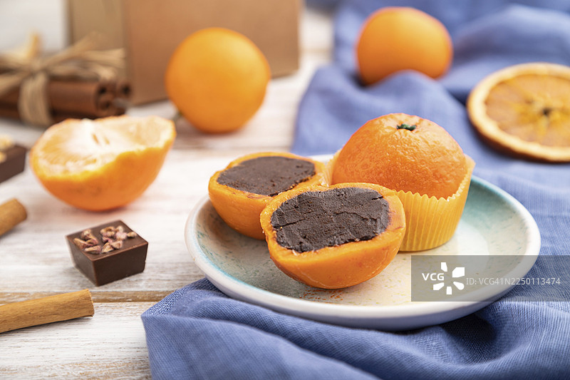 白色木质背景和蓝色亚麻织物上的松露巧克力橘子糖果。侧视图，特写，选择性对焦图片素材