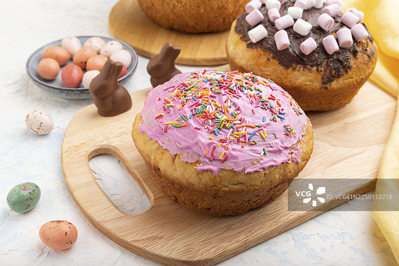 白色混凝土背景上装饰着巧克力彩蛋和兔子的自制糖霜复活节馅饼，配有黄色纺织品。侧视图，特写图片素材