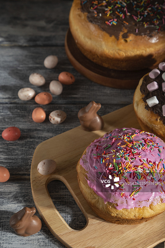 自制糖霜装饰的复活节派，搭配巧克力彩蛋和兔子，置于灰色木质背景和亚麻布上。硬光，高对比度，侧视图，特写图片素材