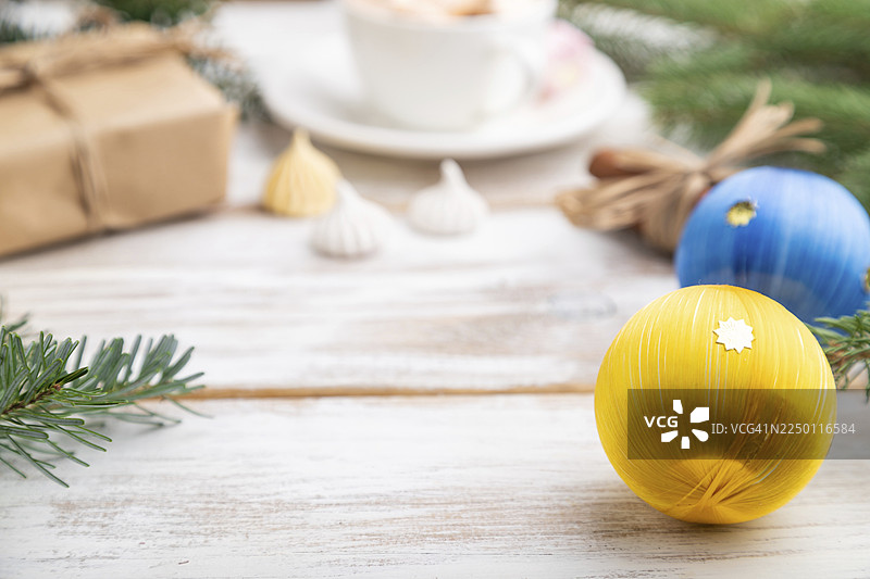 圣诞节或新年主题的框架构图。装饰品、盒子、球、肉桂、丝带、冷杉和云杉枝,以及一杯咖啡,摆放在白色的木质背景上。侧面视角,留有复制空间,焦点选择性。图片素材