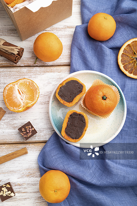 白色木质背景和蓝色亚麻纺织品上的松露巧克力橘子糖果，俯视，平铺，特写图片素材