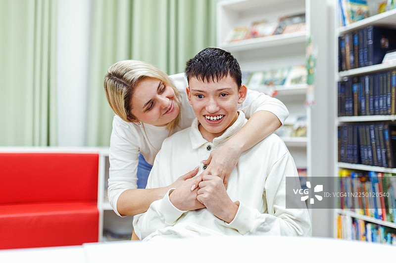 温馨的家庭时刻，一位母亲在图书馆拥抱患有自闭症谱系障碍的儿子图片素材