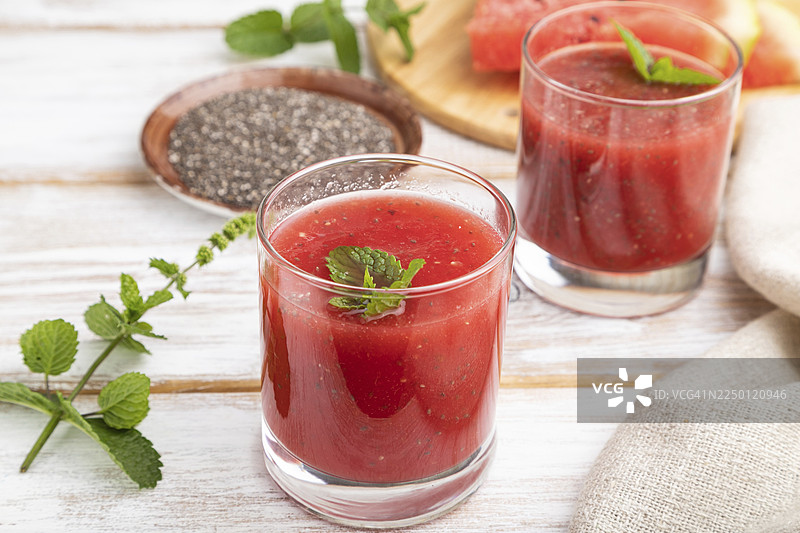 亚麻布背景上放着西瓜汁、奇亚籽和薄荷的玻璃杯，健康饮品概念。侧视图，特写。图片素材