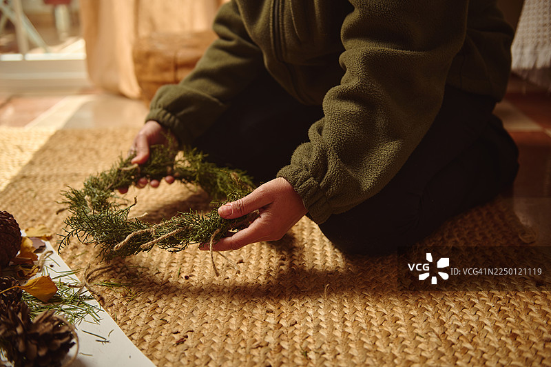 地板上的人在舒适的家中制作常青藤花环图片素材