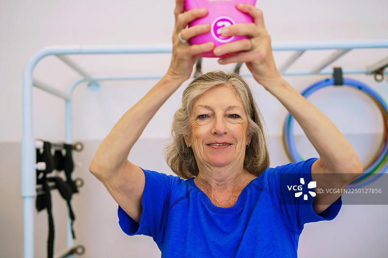 老年女性在健身房用粉色杯子锻炼图片素材
