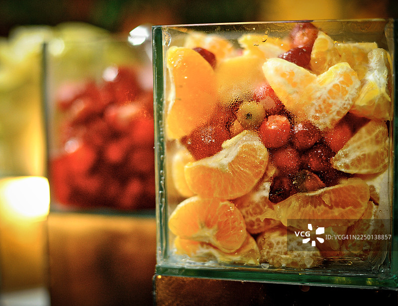 一个装满橙子和浆果等什锦水果的玻璃容器,因寒冷而蒙上雾气。准备饮料的配料。特写。图片素材