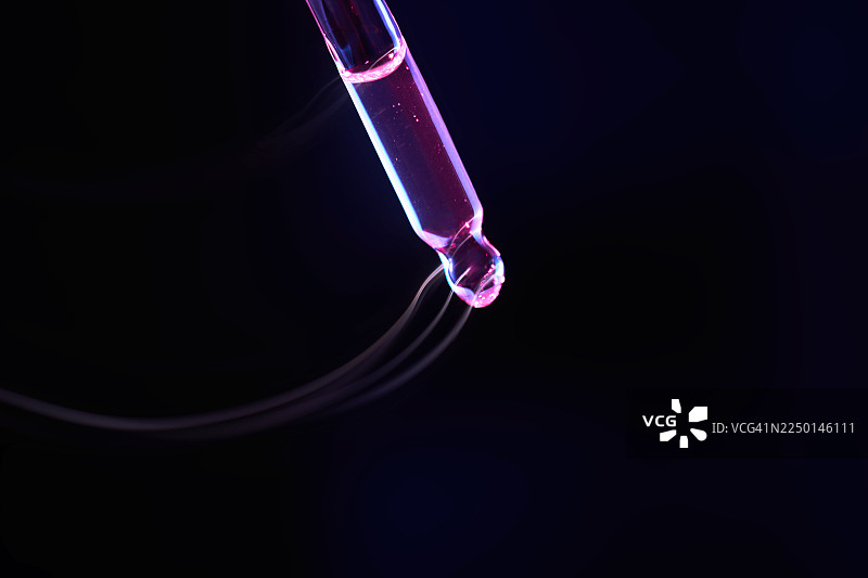 用于生物技术研究的滴有粉色面部精华的移液管图片素材
