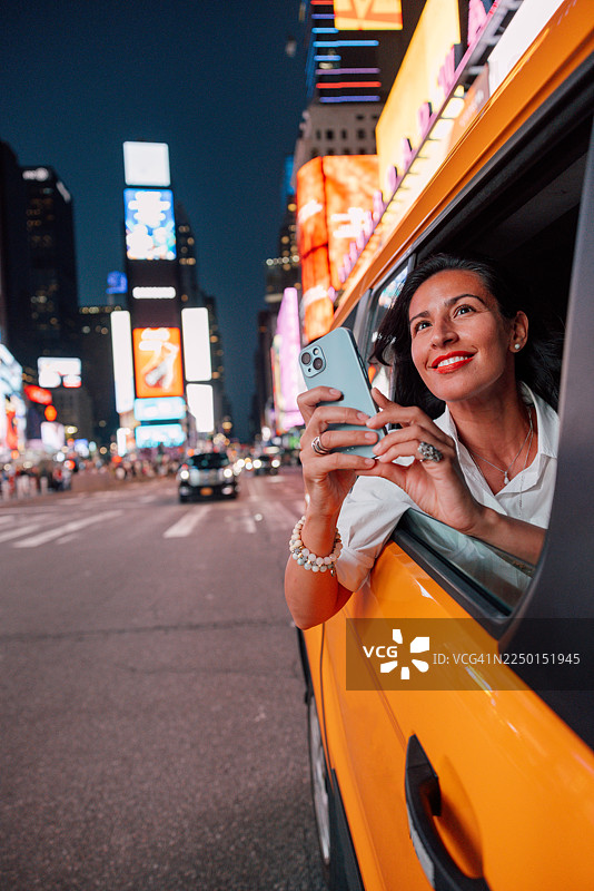 游客在曼哈顿的出租车车窗外捕捉时代广场的夜景图片素材