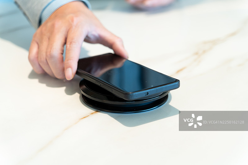 手机在桌子上无线充电器上充电图片素材