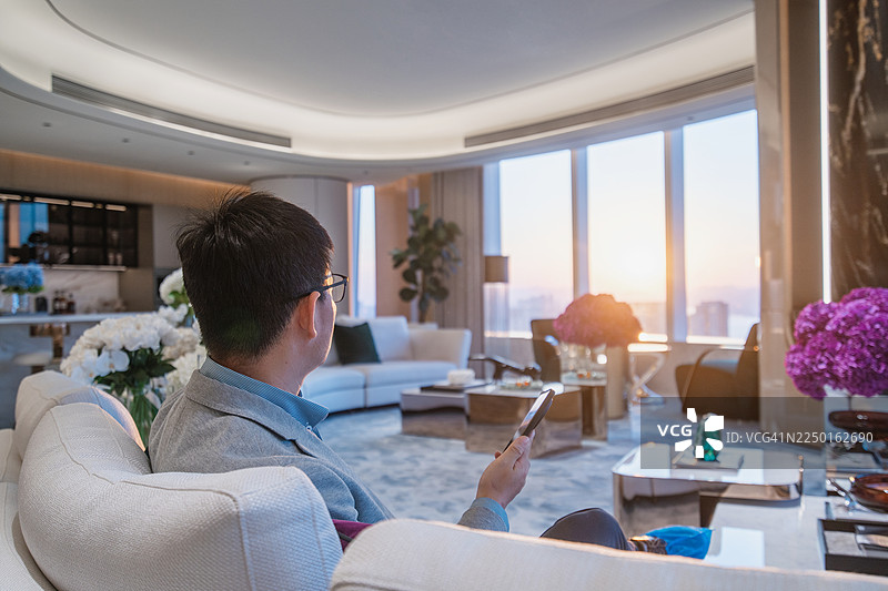 一位亚洲商人坐在椅子上使用智能手机图片素材