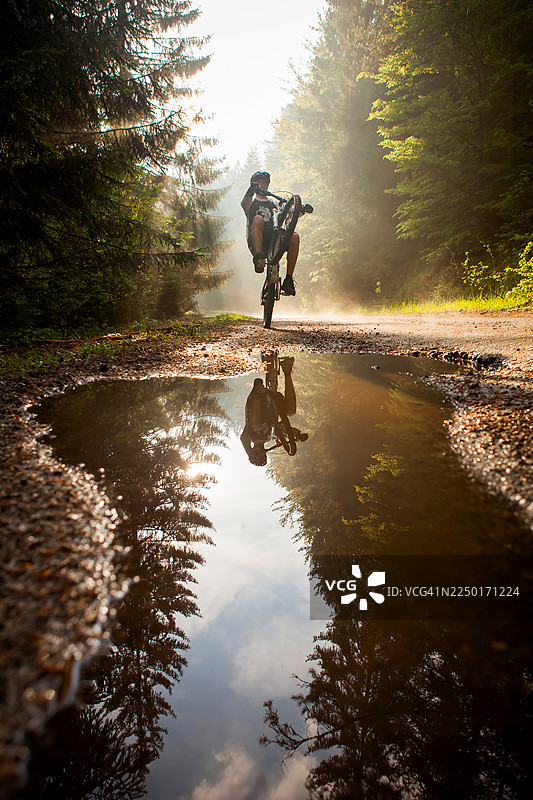 山地车骑手在水坑旁翘起前轮图片素材