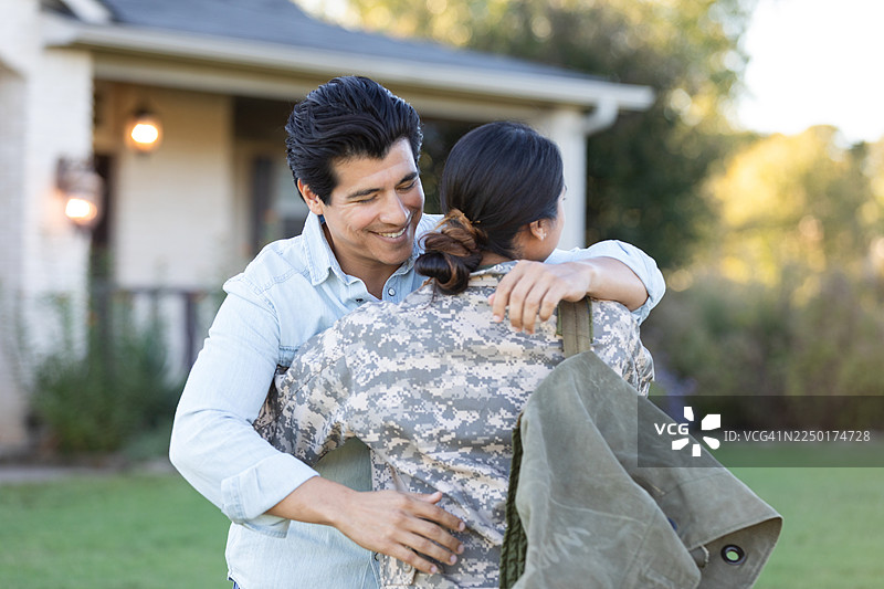 一位军人退伍回家，与家人在屋外喜悦重逢。图片素材