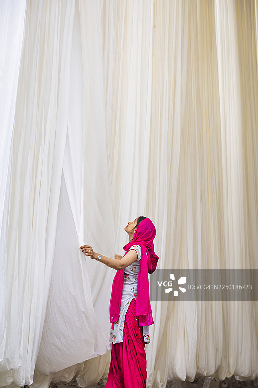 印度斋浦尔，女子正在晾晒白色的亚麻织物图片素材