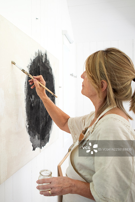 一位成熟的女艺术家正在她的画室里创作图片素材