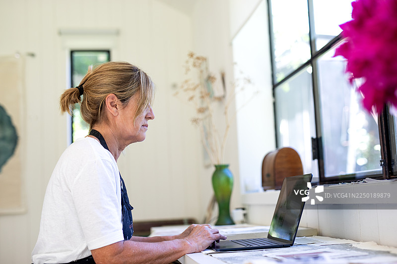 一位成熟的女企业家在她的工作室里使用科技产品工作图片素材