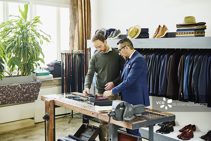 中景镜头，男顾客和裁缝正在为西装挑选面料图片素材
