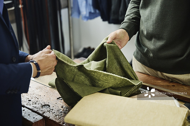 中景特写男士手部，手持并触摸亚麻布料样品图片素材