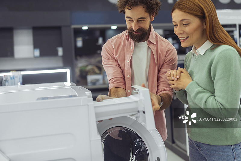 一对快乐恩爱的夫妇正在检查洗衣机的洗涤剂分配器图片素材