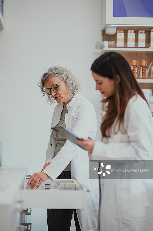 药剂师导师在药房培训年轻女性盘点库存图片素材