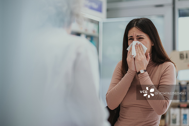 一位女士在药店里擤鼻涕并寻求帮助图片素材