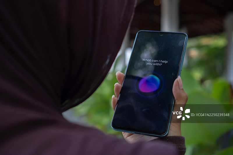 穆斯林女性用智能手机使用语音助手图片素材