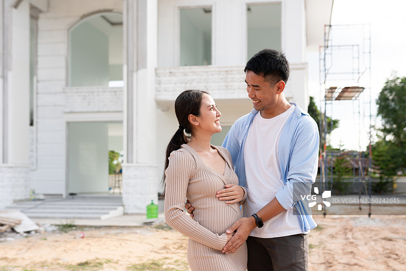 一对幸福的准父母在正在建设中的新家前拥抱图片素材