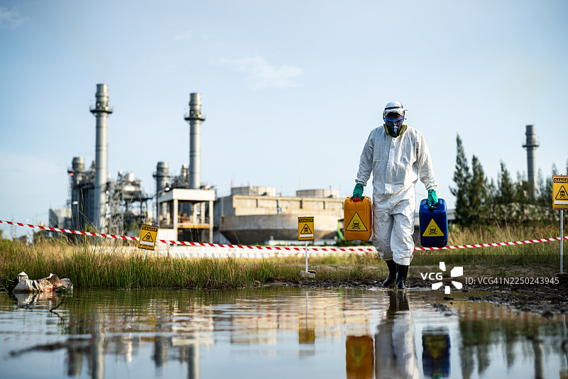危险废物专家在工厂附近的污染水域中行走图片素材
