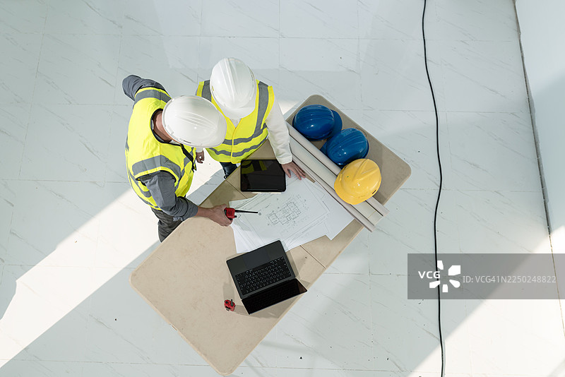 高角度拍摄，两名工程师在建筑工地协作研究蓝图图片素材