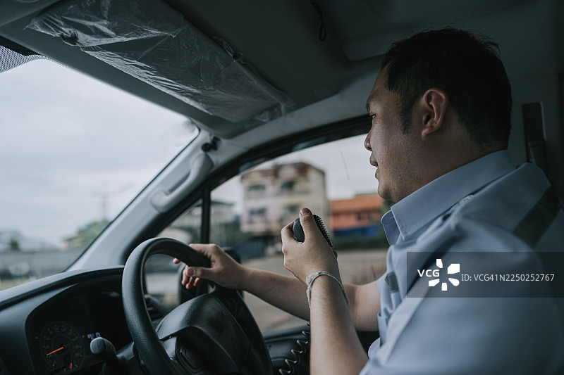 亚洲男性救护车司机在驾驶时通过无线电通话图片素材
