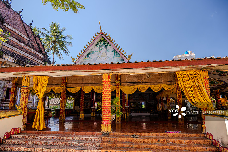 老挝万荣装饰华丽的寺庙大厅，垂挂着金色帷幔，廊柱精雕细琢。图片素材