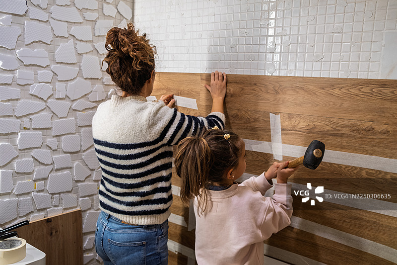 母女俩在墙上安装木质墙板图片素材