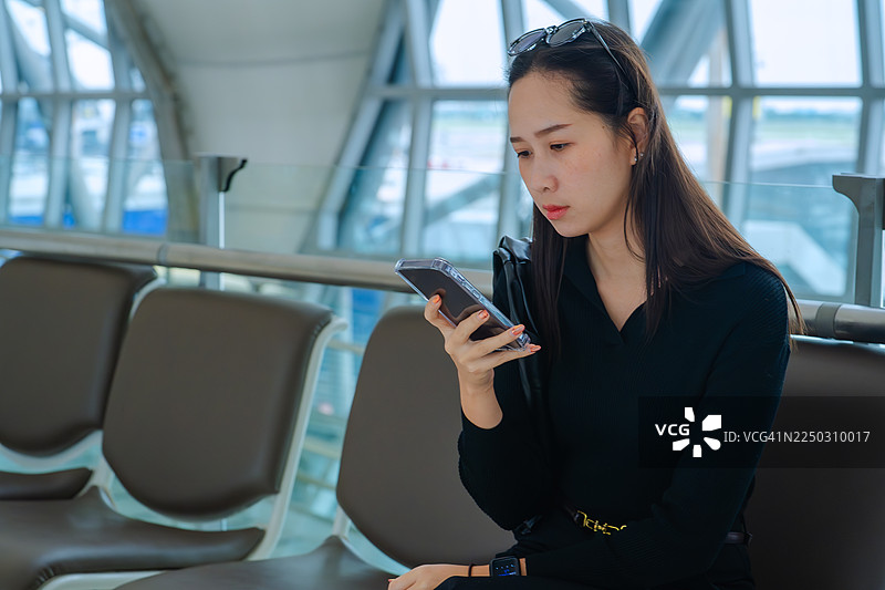 年轻女子在机场候机时使用智能手机图片素材