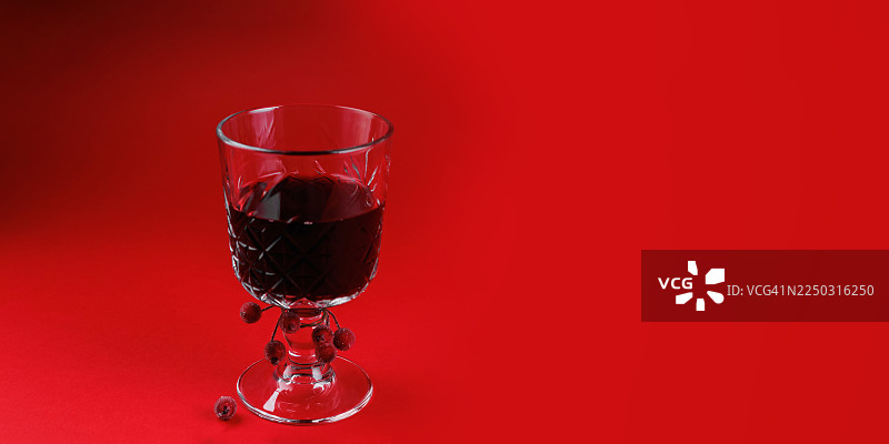 红色表面的酒杯，周围散落着红色浆果图片素材