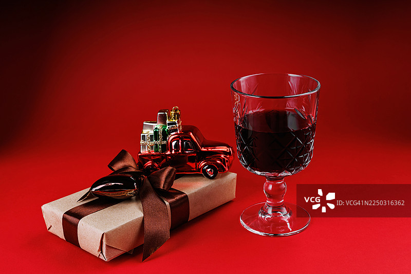 红背景上的圣诞礼物、酒杯和玩具卡车图片素材