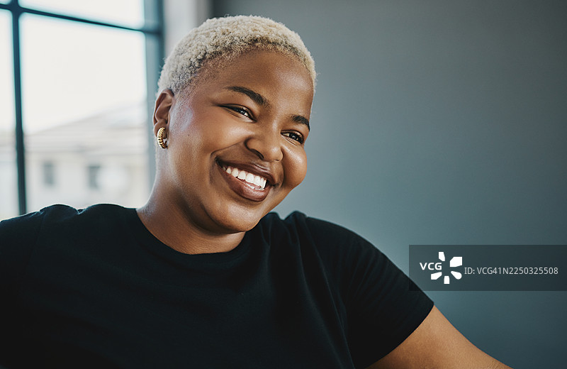 室内，一位金发女子穿着休闲黑衬衫，面带微笑，展现健美曲线的肖像照图片素材