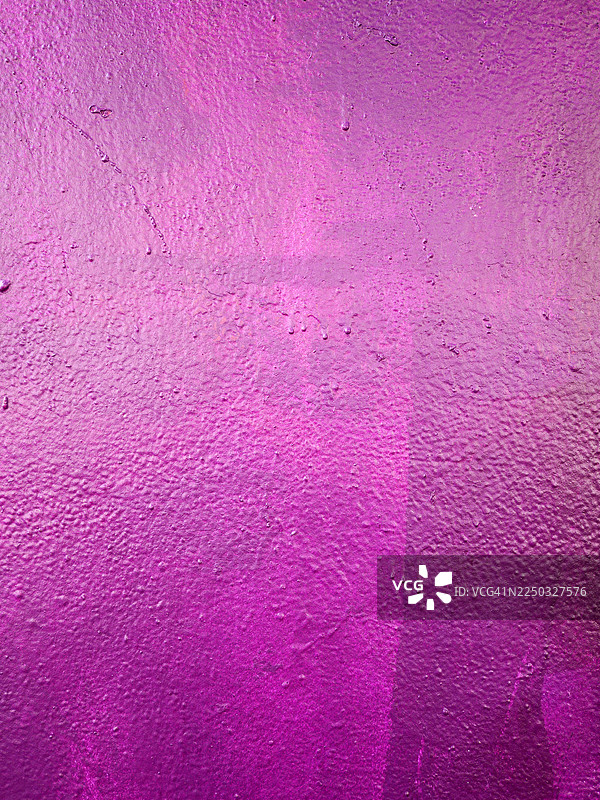 明亮的紫色混凝土墙，带有涂漆和做旧效果。纹理粗糙。自然光和色彩。法国巴黎。图片素材