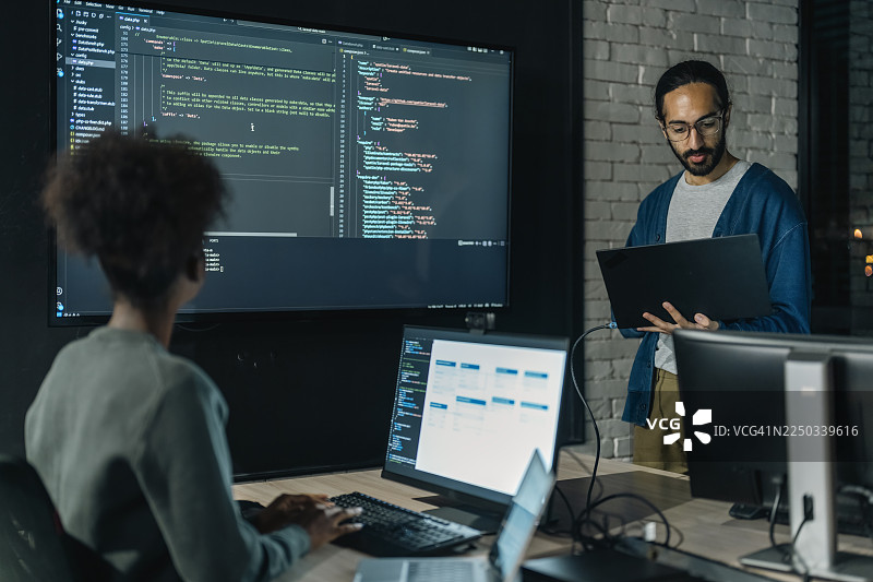 软件工程师在办公室合作项目，讨论客户需求概念、工作流程图，并在电脑显示器上分析代码图片素材
