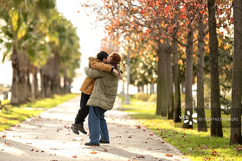一个孩子跑进城市公园，跳进妈妈的怀抱并拥抱她。系列照片的一部分图片素材