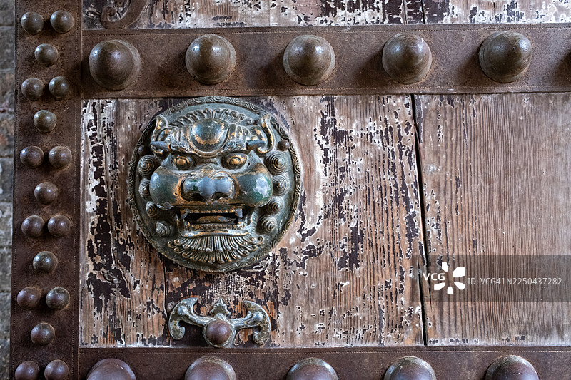 古铜狮子门环，装饰在饱经风霜的木门上图片素材