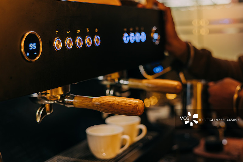 咖啡师在温馨的咖啡馆环境中操作专业浓缩咖啡机。图片素材