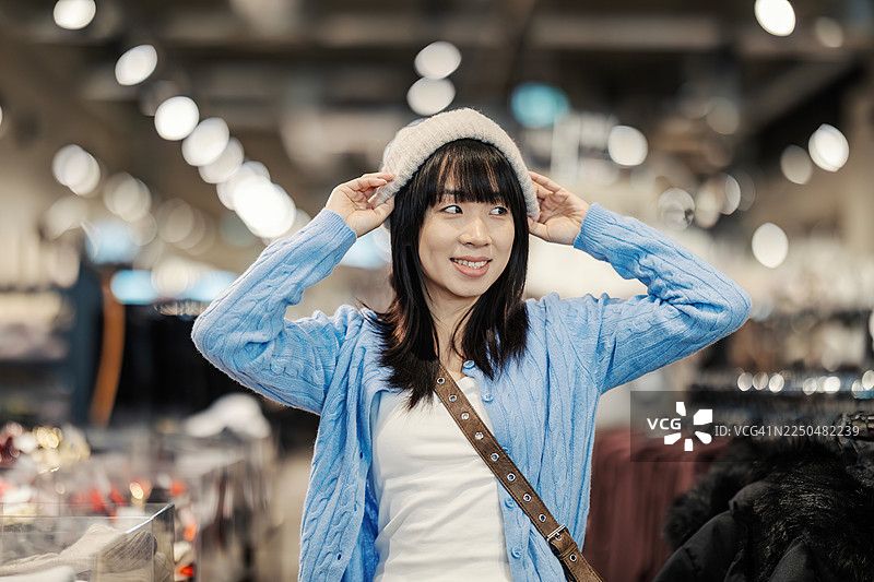 女子在服装店试戴舒适的绒线帽图片素材