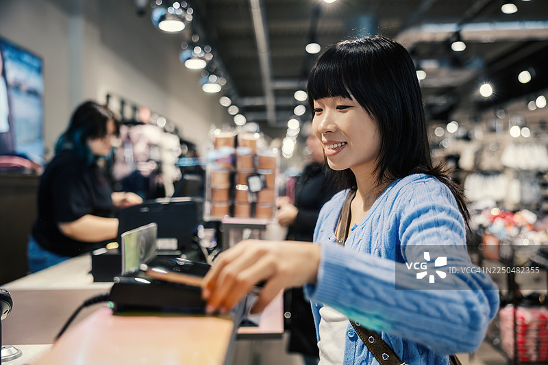年轻女子在商店收银台进行非接触式支付图片素材
