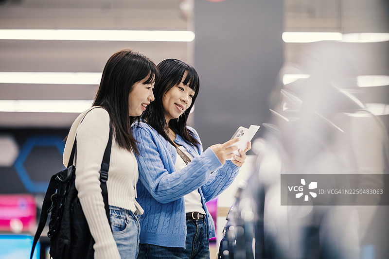 两位年轻女性在选购新款智能手机图片素材