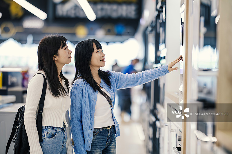 两位女性在电器商店选购现代家居电器图片素材