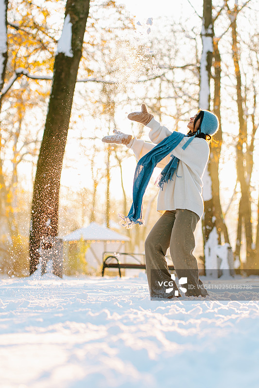 女人在冬天的公园里玩耍，开心地抛洒着雪花图片素材