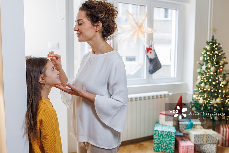 妈妈在家给女儿量身高图片素材
